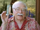 Irving Dayton, an older man with glasses and white hair looks at the camera. 